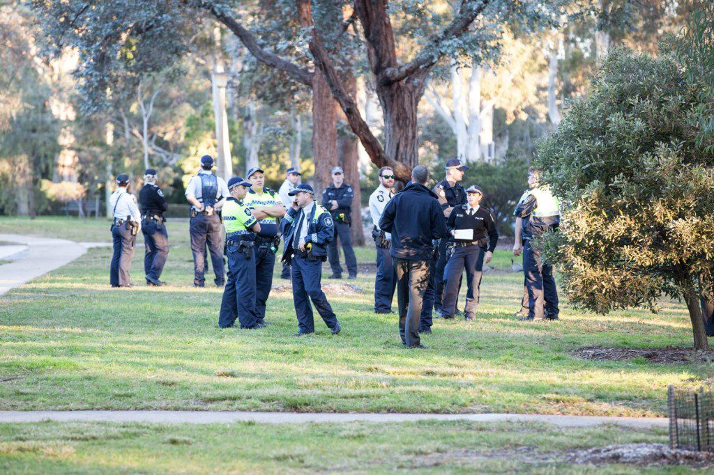 Australian Federal Police officers wait across the road from the Chancelry buildings