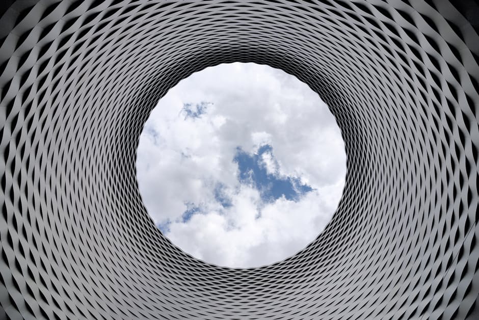Architectural structure looking up through a tunnel to the sky.