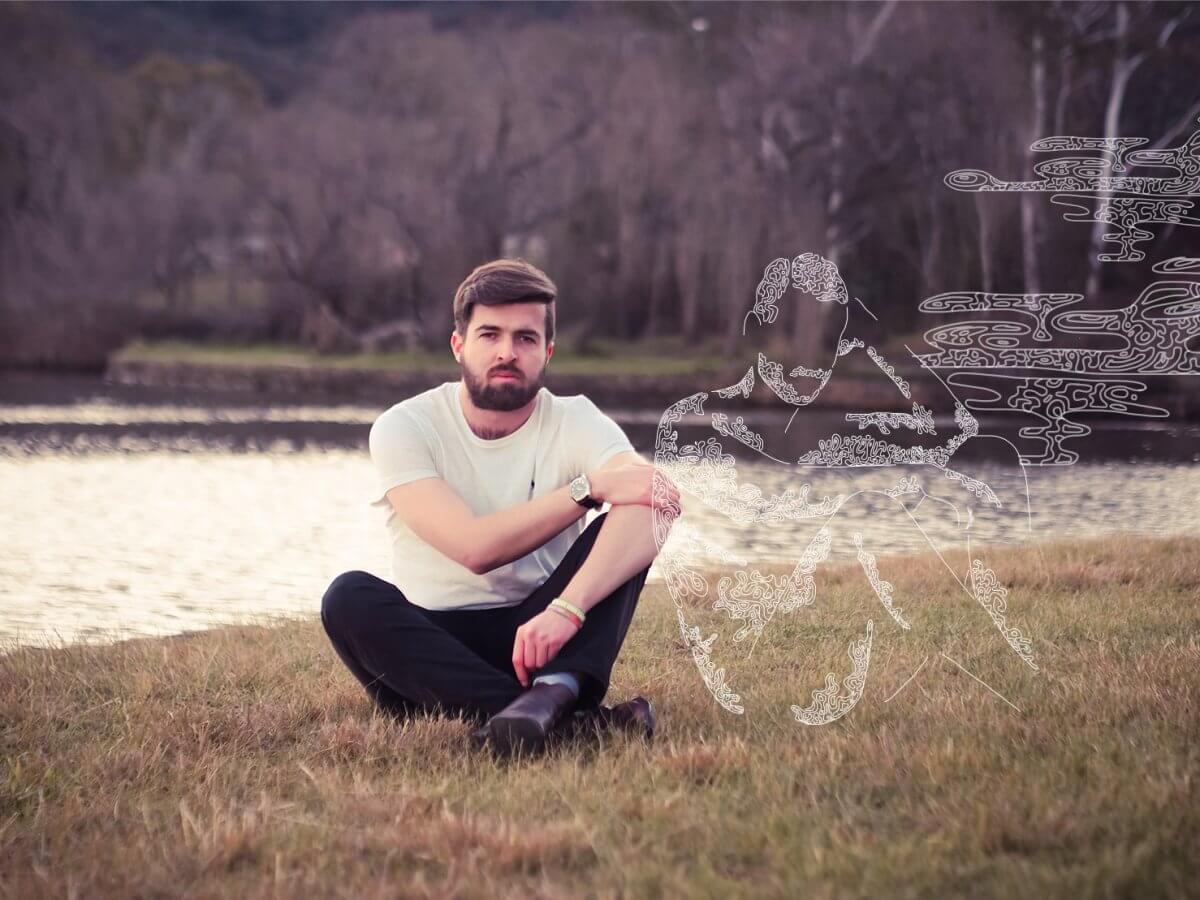 ANUSA President James Connolly sits by a river. A graphic of a male figure outlined in white sits beside him.