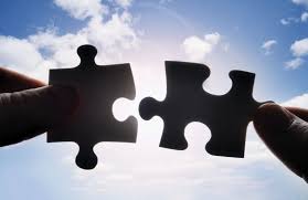 teo jigsaw piece being held up to the sky, silhoutetted