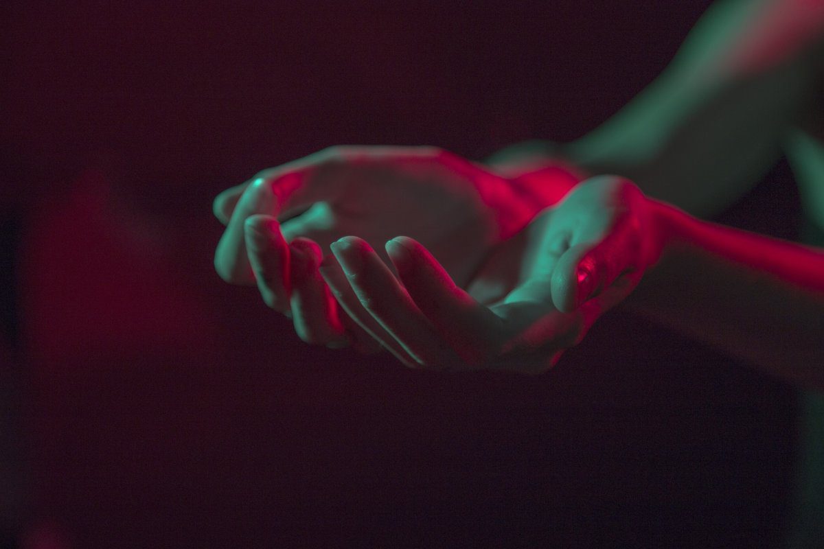 Two hands cupped together under a blue-red light