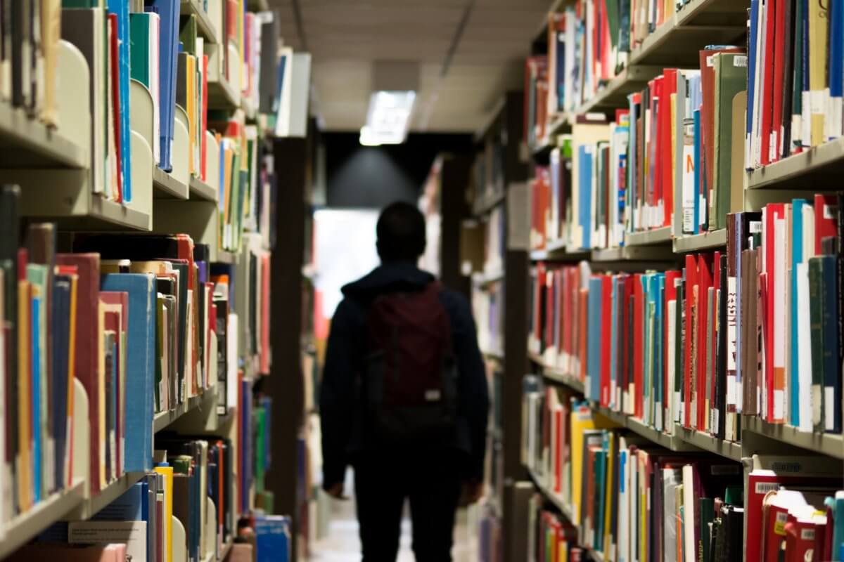 silhouette in between library shelves with books