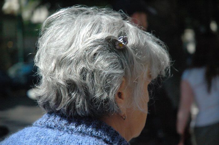 Back of an elderly woman's head, showing her grey hair.