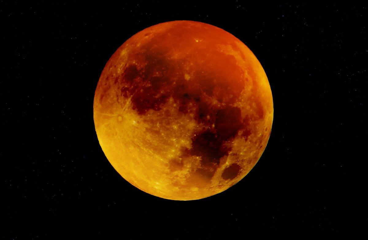 Blood moon against black sky.