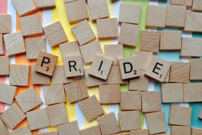 Scrabble tiles spelling 'pride' on a rainbow background.