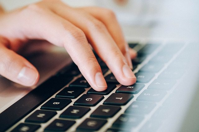 close up on hands typing on a mac laptop