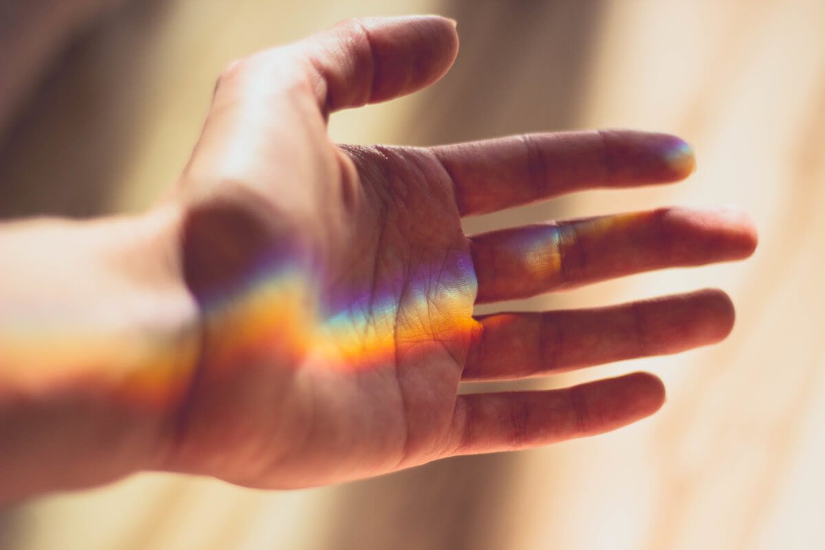 Rainbow light projected on a person's outstretched left hand