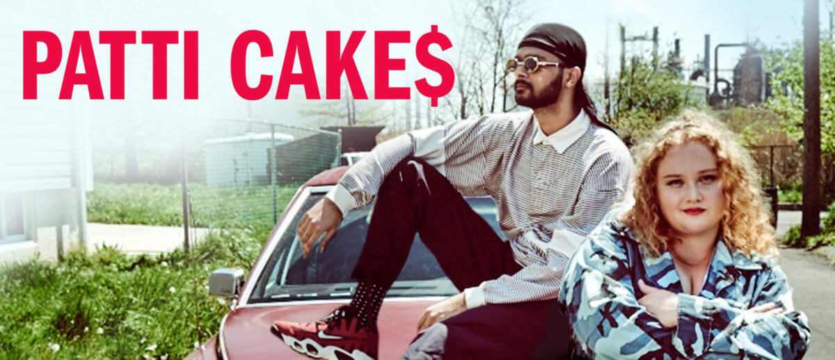 A promo shot from the movie, Patti Cakes, featuring the two main stars sitting on a red car.