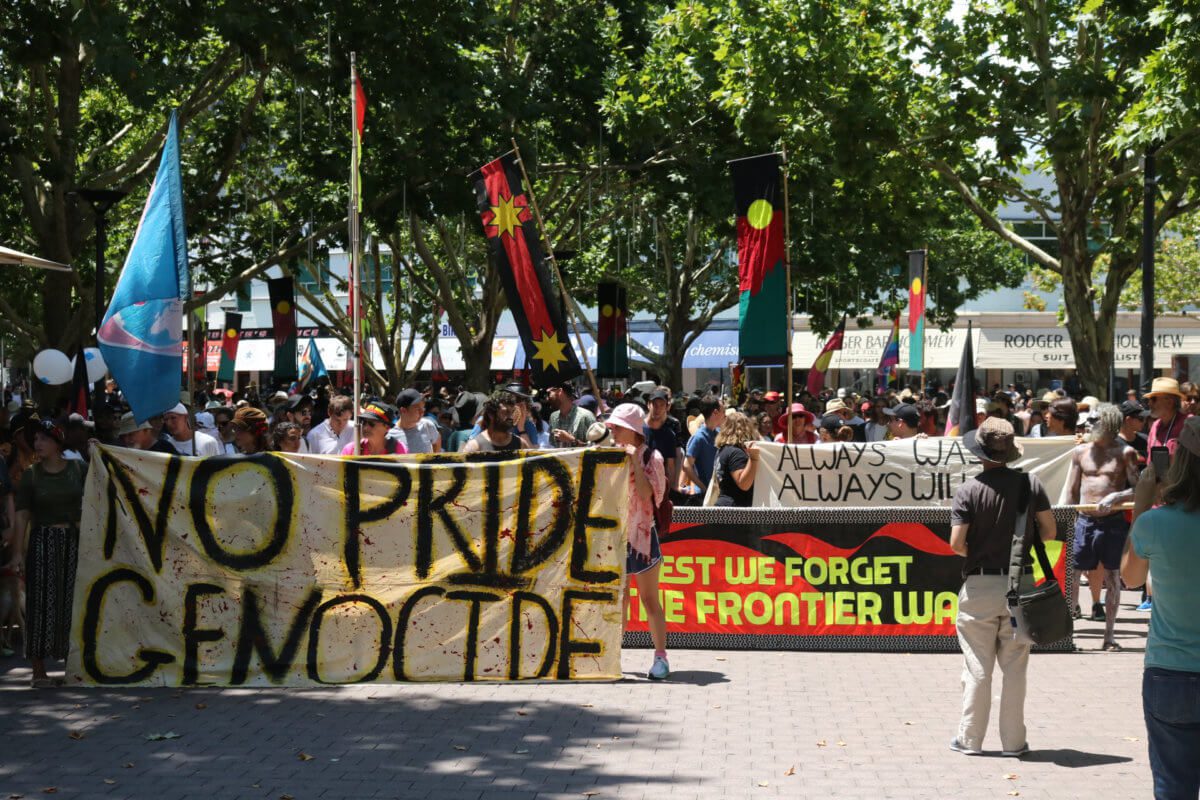Photo of large crowd at a demonstration, banners read No Pride in Genocide, Lest We forget the frontier war and always was, always will be
