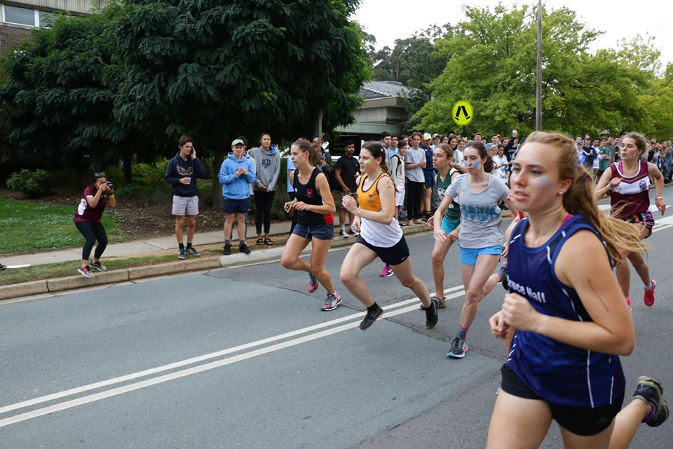 Five runners break from the start line at road relay, wearing uniforms from different ANU Halls