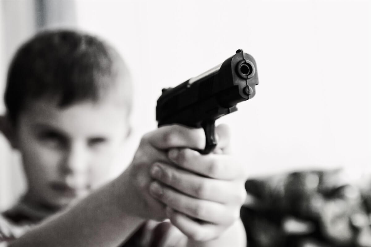 black and white picture of a child holding a gun