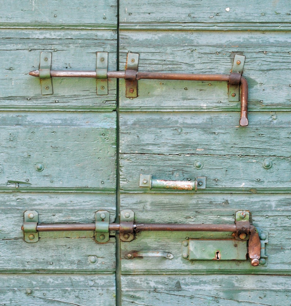 Two locks on a wooden door with blue flaking paint
