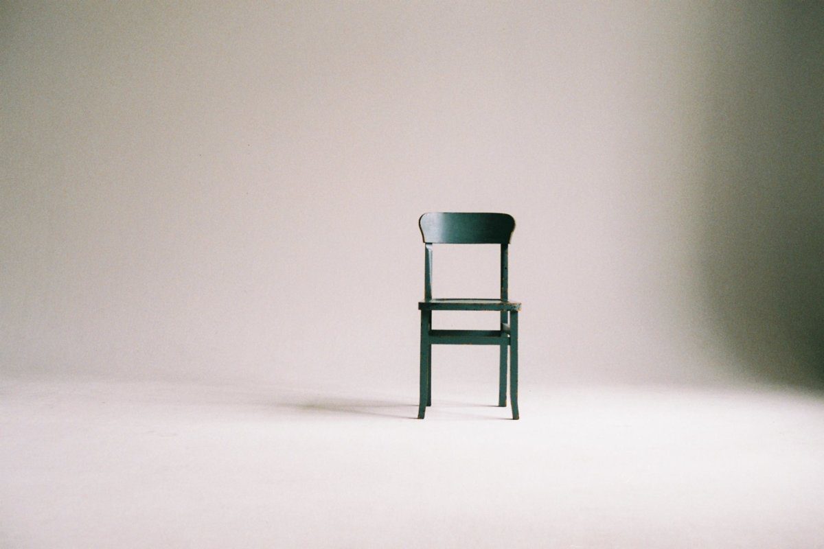 A green wooden chair in an empty room