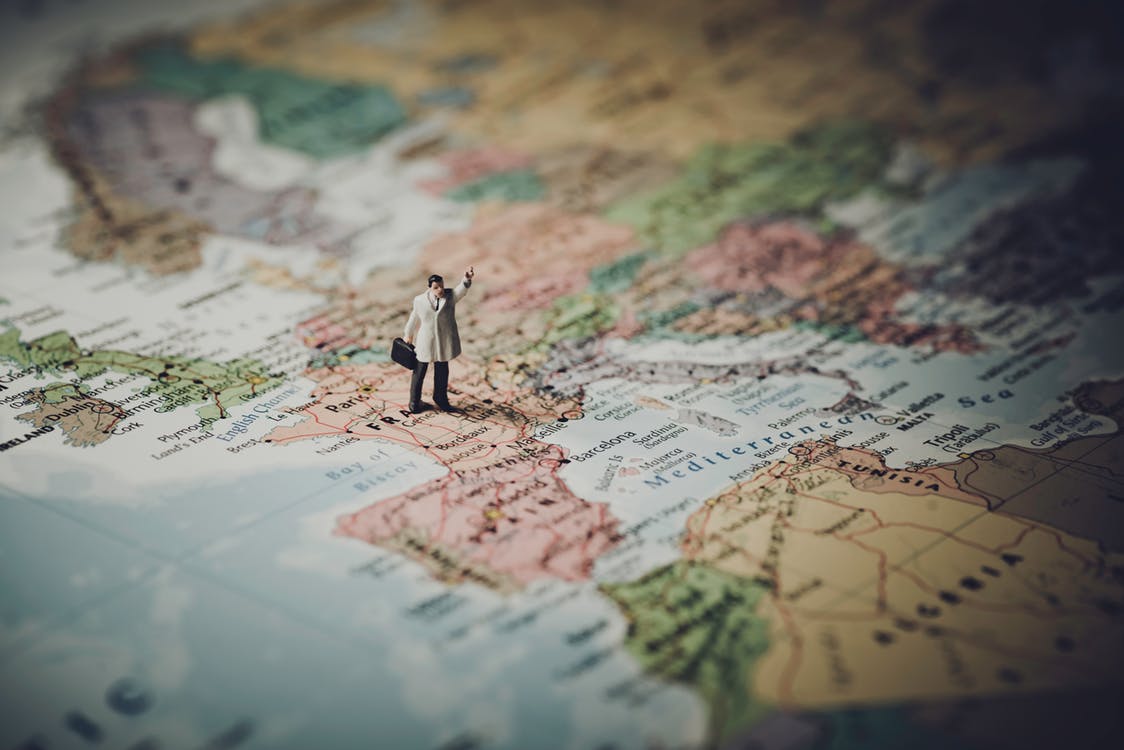 Miniature of man with briefcase standing on the map of the world