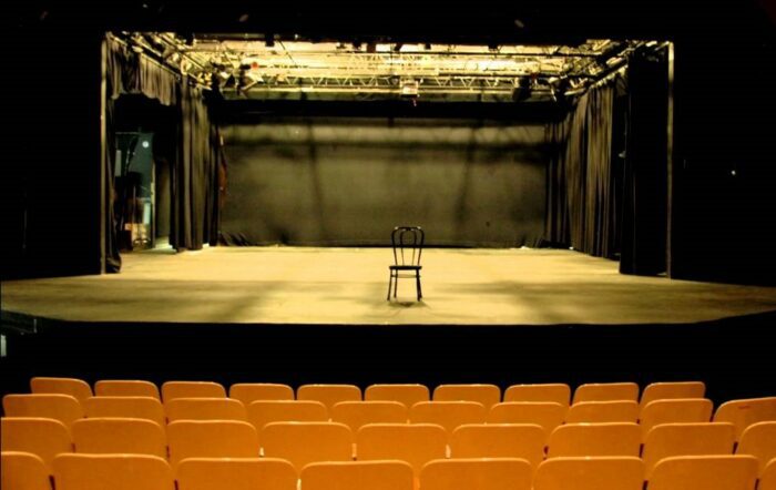 A photograph on of an empty theatre with a chair centre stage